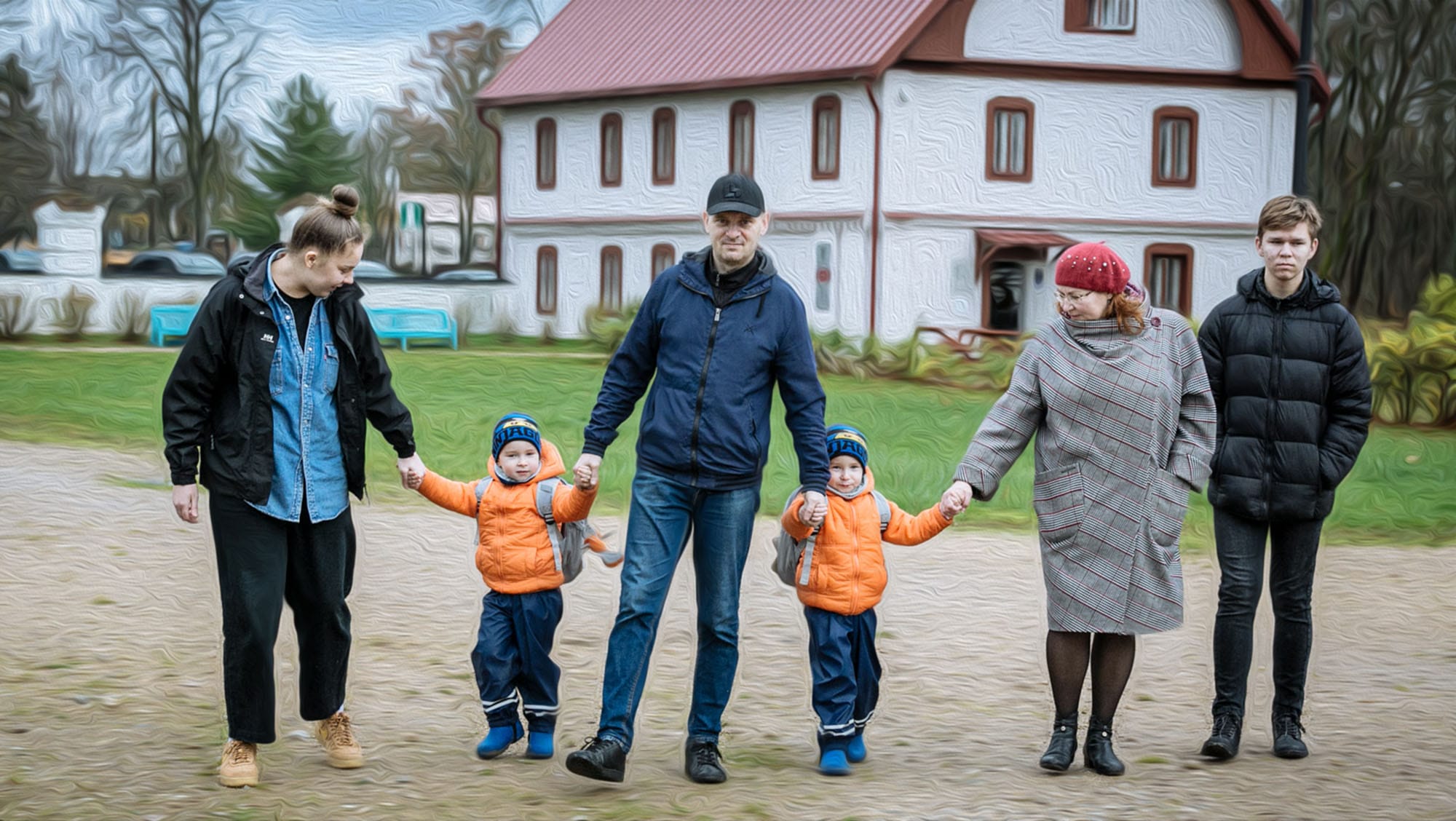 A family of six holding hands outdoors near a building with a red roof. Two adults are in the center with young children in orange jackets, while an adult and a teenager are on each side, all dressed for cool weather.